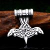 The Odins Ravens Pendant Amulet Necklace features a silver Thor’s hammer with Norse knotwork, stylized animal heads, and subtle Odin’s ravens, displayed on wood against a dark background.
