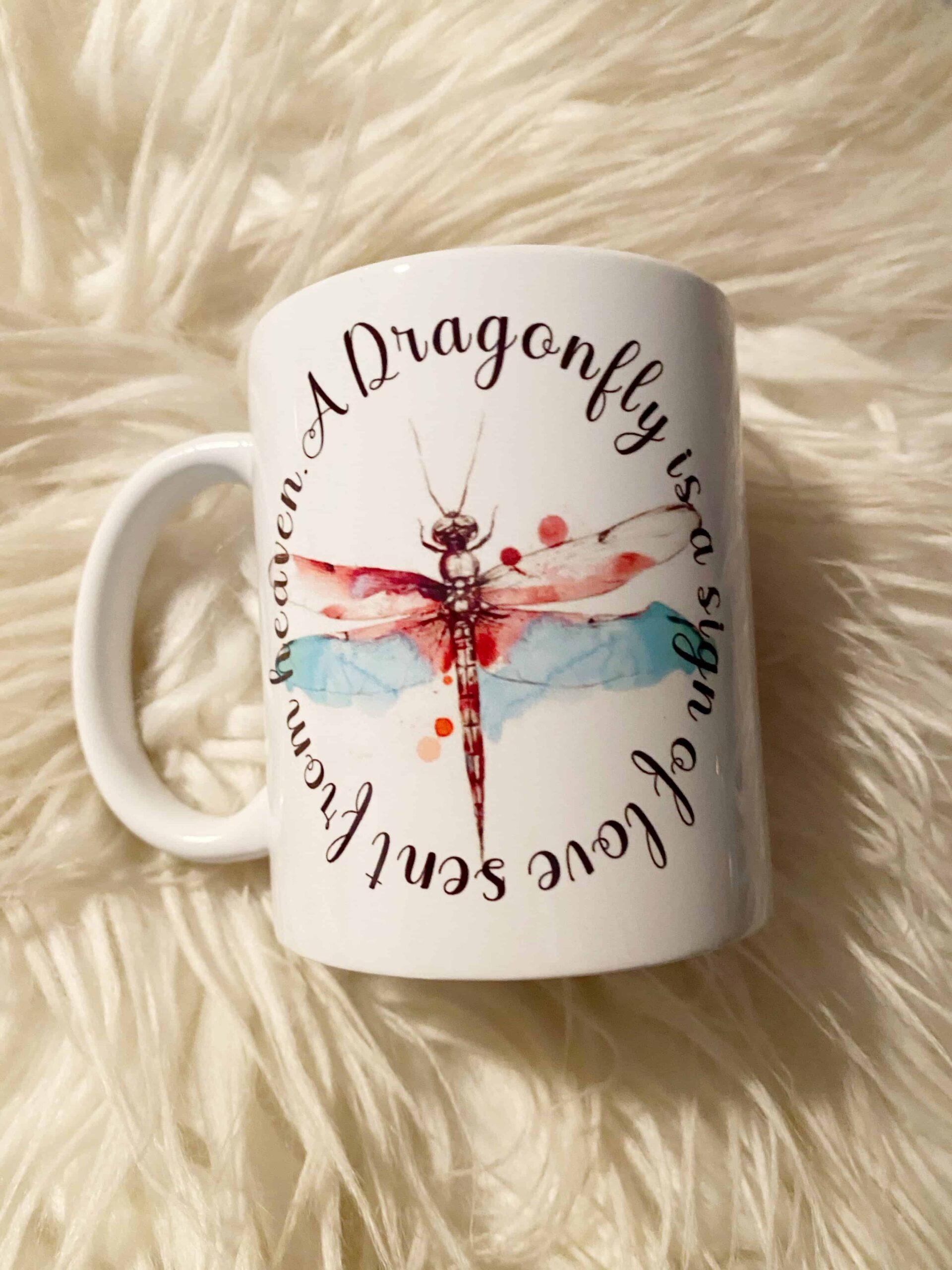The Dragonfly love from heaven mug features a colorful dragonfly and the phrase A dragonfly is a sign of love sent from heaven in a circular pattern—perfect for anyone who believes in the magic of dragonflies.