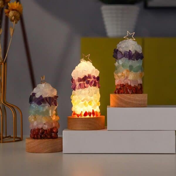 Three vibrant Crystal Lamps with star-shaped toppers sit on wooden bases; the middle Crystal Lamp glows warmly. All are displayed on a white surface against a softly blurred background.