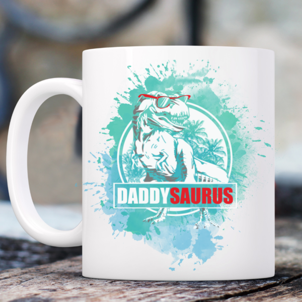 The Daddysaurus Fathers Day Mug features a cartoon T. rex in sunglasses with palm trees and blue splashes, plus “DADDYSAURUS” in green and red—a fun, playful gift for Dad on Fathers Day.