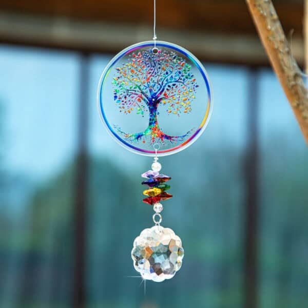 The Chakra Tree of Life Suncatcher, decorated with vibrant crystal beads and a faceted crystal ball, hangs beautifully and sparkles in sunlight against a softly blurred outdoor backdrop.