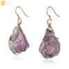 Natural Stone wire wrapped earrings featuring raw purple natural stones with a gold wire wrap and simple gold hooks. The stones have an unpolished, organic look.