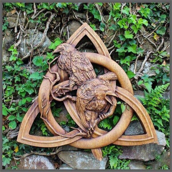 Odin Ravens Wall Carving The Odin Ravens Wall Carving features two wooden ravens on intertwined branches within a Celtic triquetra knot, perfect for hanging on any wall adorned with ivy and ferns.
