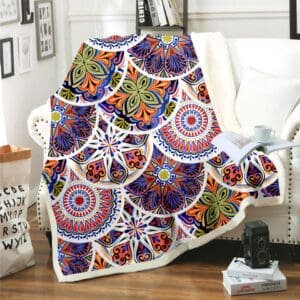 The Boho Mandala Blankets feature vibrant blue, red, orange, and green geometric and floral patterns, adding a cozy touch when draped over a white couch in a stylish living room with decor and books.