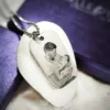 The Custom Dog Tag Necklace features an engraving of a man holding a baby, beautifully displayed on a white stone with a purple background.