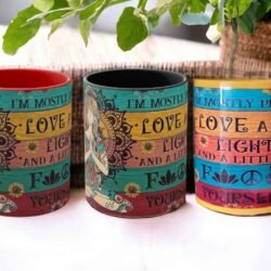 Three Mostly Peace Love N Light & A Little Go F yourself Mugs with floral designs are displayed side by side on a table, with a green plant in the background.