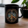 A Vegvisir Worldtree Black Ceramic Mug with a vibrant Norse design, showcasing Yggdrasil and runes, rests on a wooden table next to a small black plant pot.