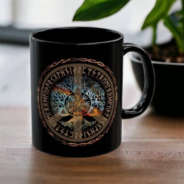 A Vegvisir Worldtree Black Ceramic Mug with a vibrant Norse design, showcasing Yggdrasil and runes, rests on a wooden table next to a small black plant pot.