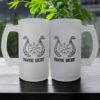Two Viking Dragon Boat Frosted Glass Beer Mug Personalised rest on a dark table, each with dragon designs, runic symbols, and NAME HERE below. A green plant and an outdoor background complete the scene.