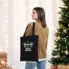 Christmas Gnomes Classic Tote Bag A woman wearing a tan jacket stands by a decorated Christmas tree and wrapped gifts, holding the Christmas Gnomes Classic Tote Bag featuring “Merry Christmas” and festive gnome designs.