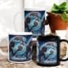 Two white and one black Aquarius Aboriginal Art Zodiac Mug feature an artistic Aquarius pouring water with dolphins and waves. The mugs are displayed beside a potted plant and some logs.