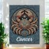 The Cancer Crab Aboriginal Astrology Art Canvas showcases a stylized crab with intricate dot patterns, inspired by Aboriginal astrology. Cancer appears below the artwork, which is beautifully displayed between two plants.