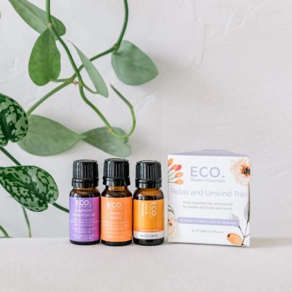Relax and Unwind Essential Oil Trio Pack Three bottles from the Relax and Unwind Essential Oil Trio Pack are arranged on a white surface, surrounded by green vine leaves, inviting relaxation and calm.