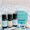 ECO Little Calm and Focus Three small essential oil bottles stand before a blue and teal ECO Little Calm and Focus box on a blue-tiled surface, with dried flowers scattered nearby for a serene touch.