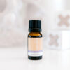 A small amber bottle with a black cap, labeled ECO Little Lullaby, rests on a white surface with blurred blocks in the background.