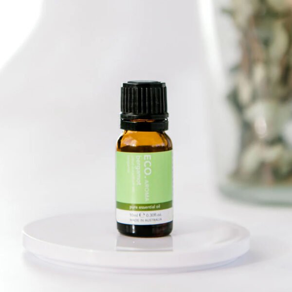 Rest and Glow Essential Oil Trio Pack A small amber glass bottle of Bergamot Pure Essential Oil rests on a white surface with a blurred background.