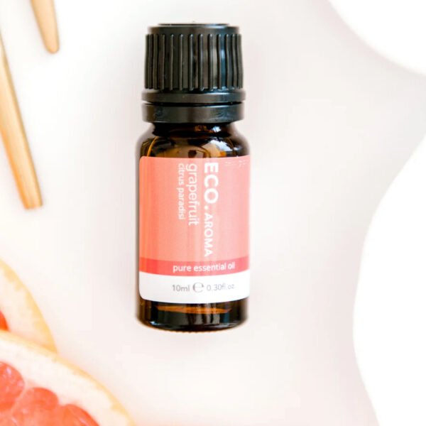 Rest and Glow Essential Oil Trio Pack A small amber bottle of Grapefruit Pure Essential Oil rests on a white surface, surrounded by fresh grapefruit slices and two wooden sticks.