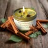 Abundance Intention Candle - Cinnamon, Patchouli, Citrine, Pyrite tin candle An Abundance Intention Candle - Cinnamon, Patchouli, Citrine, Pyrite tin candle in a gold tin sits on wood, surrounded by cinnamon sticks, star anise, and green leaves. The candle features citrine stones and a gold coin to inspire abundance.