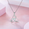 A silver necklace featuring a Celtic trinity knot pendant with a round opal stone in the centre, displayed on a soft pink background.