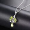 Peridot 3 Tier Sterling Silver Pendant Necklace The Peridot 3 Tier Sterling Silver Pendant Necklace features a branch-shaped pendant with three green teardrop peridot gemstones, displayed on a matte black surface.