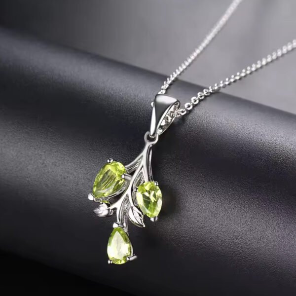 Men’s Compass Necklace The Peridot 3 Tier Sterling Silver Pendant Necklace features a branch-shaped pendant with three green teardrop peridot gemstones, displayed on a matte black surface.
