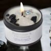 Peace & Protection - White Sage & Frankincense Candle The Peace & Protection - White Sage & Frankincense Candle, adorned with black and white crystals and an evil eye charm, sits beside White Sage and a black stone—ideal for rituals promoting peace and protection.