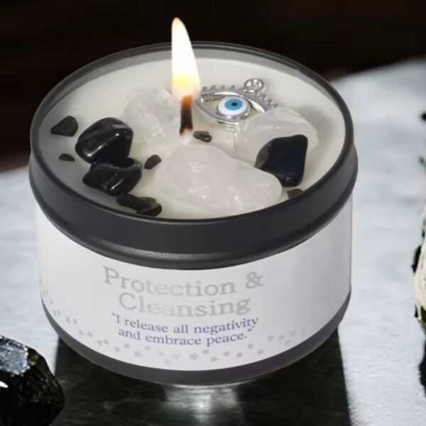 Crystal Moon Suncatchers The Peace & Protection - White Sage & Frankincense Candle, adorned with black and white crystals and an evil eye charm, sits beside White Sage and a black stone—ideal for rituals promoting peace and protection.