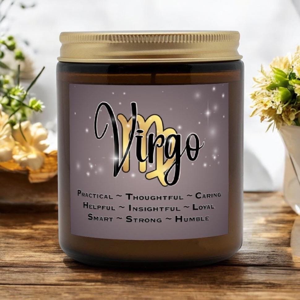 A brown candle jar with a label that says Virgo over a yellow Virgo symbol. Below, words list traits: Practical, Thoughtful, Caring, Helpful, Insightful, Loyal, Smart, Strong, Humble. Flowers are in the background.