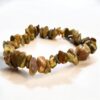 Rhyolite Chip Bracelet – Healing Crystal Jewellery The Rhyolite Chip Bracelet – Healing Crystal Jewellery features polished, irregular brown and green stones on an elastic band. Displayed on a white surface, it is believed to have healing properties.