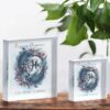 Two clear acrylic blocks featuring a Pisces Moon design with two blue fish circling a moon and astrological symbol, displayed on a white surface with green leaves in the background.